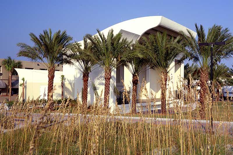 Exterior photo of Sea Walk Pavilion. Palm trees and tall grass obscure the view of the building.